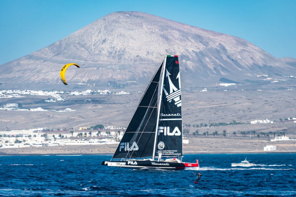 Maxi 100 Comanche powers past a kite surfer at the start of the RORC Transatlantic Race @Lanzarote Photo Sport